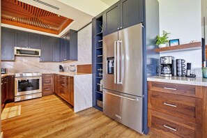 Eine moderne Küche mit einem Edelstahl-Kühlschrank, einem eingebauten Backofen und einer Mikrowelle.