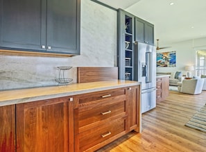 A modern kitchen with dark cabinets, a marble countertop, and a built-in refrigerator. - Kapalua Bay | Ocean View 3 BR, Sleeps 10 | Car Incl. w/ 6+ Nights | KBV ML-2089 by KBM (Lahaina)