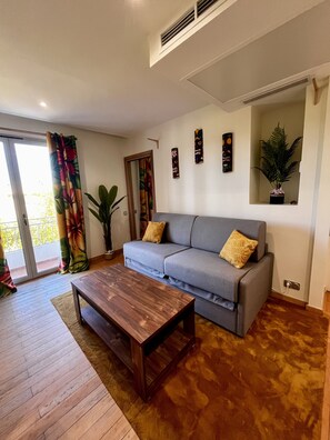 Ein Wohnzimmer mit einer Couch, einem Couchtisch, einer Pflanze und einer Schiebetür.