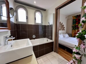 Ein modernes Badezimmer mit einer großen Badewanne, einem Waschtisch inklusive Spiegel und einer Dusche.
