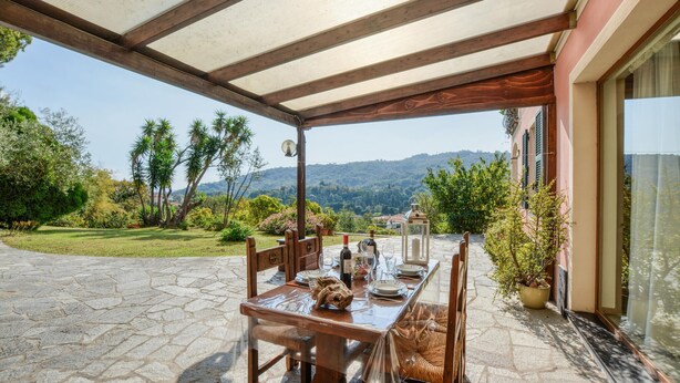Eine Terrassengruppe im Freien mit Esstisch, umgeben von Steinplattenböden und Holzmöbeln.