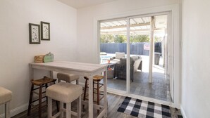 A small kitchen with a white countertop, two bar stools, and a window overlooking a patio with outdoor furniture.