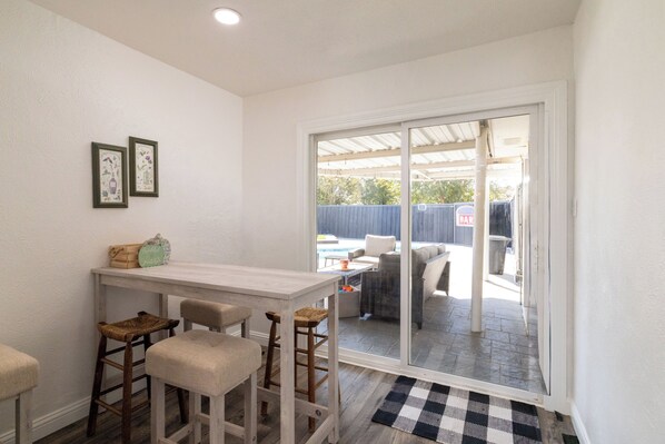 A small kitchen with a white countertop, two bar stools, and a window overlooking a patio with outdoor furniture.