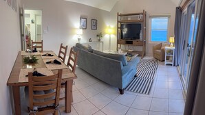 Een moderne woonkamer met een bank, eettafel en televisie.