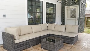 Een modulaire bank met een glazen bijzettafeltje op een betegeld terras.