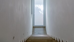 A narrow, white-walled hallway leading to a door with a frosted glass panel. - Cozy apartment in Ragusa with house sea view (Ragusa)