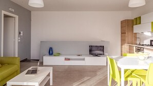 A modern living room with a TV, sofa, coffee table, and dining area with chairs. - Cozy apartment in Ragusa with house sea view (Ragusa)