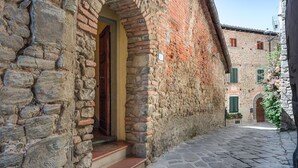 A narrow cobblestone street with a stone building featuring a wooden door and a small set of steps leading to a doorway. - Lovely apartment in Massa e Cozzile (Massa e Cozzile)