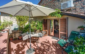 Een terras met een tafel, stoelen, een hangstoel en een grote parasol.