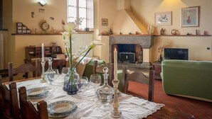 A dining area with a table set for four, surrounded by chairs. A fireplace is visible in the background, and there are various decorative items on the walls. - Lovely apartment in Massa e Cozzile (Massa e Cozzile)