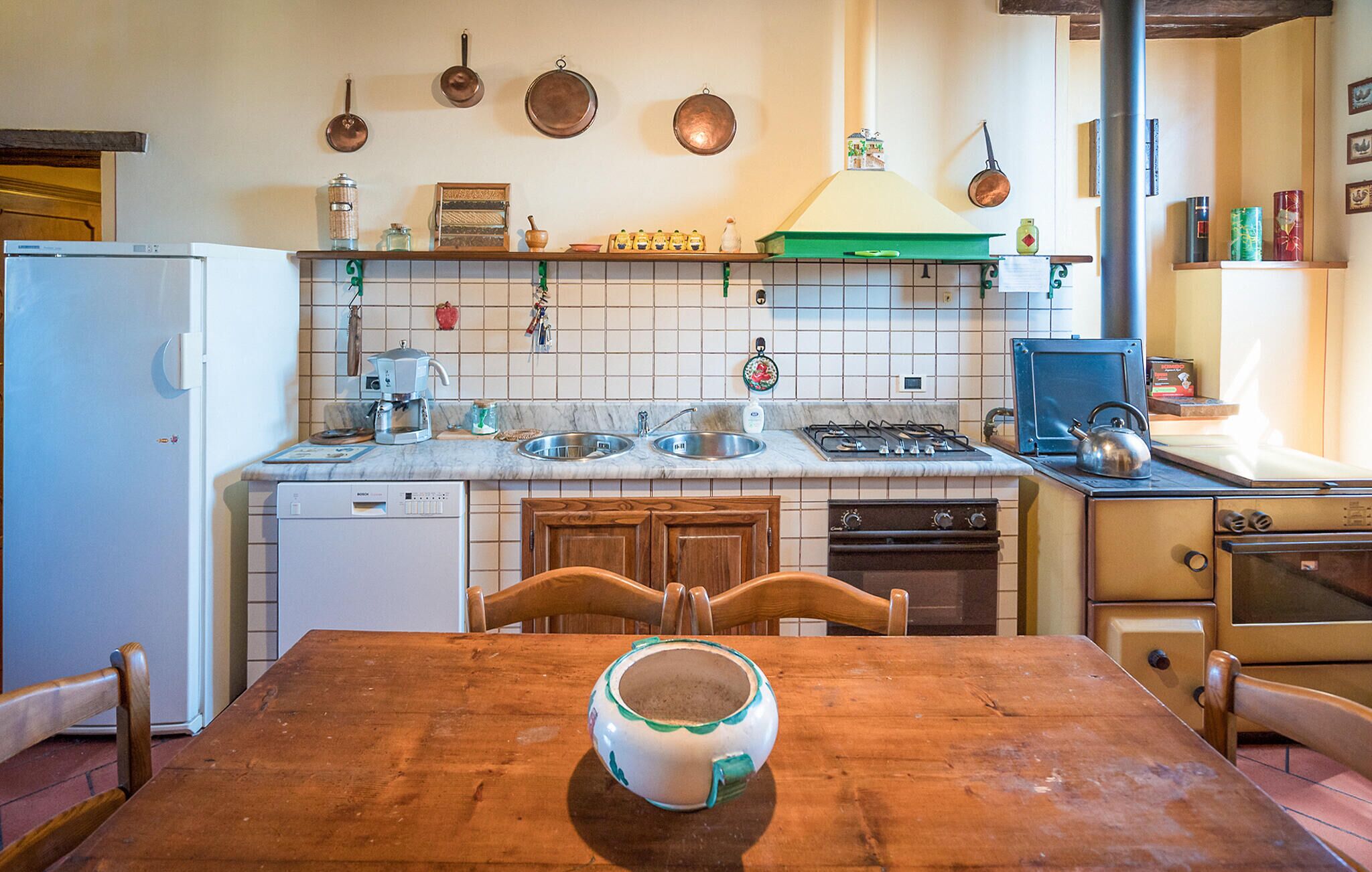 A compact kitchen with a wooden table, a Bosch dishwasher, a stove, and a sink.
