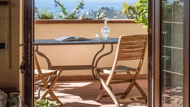 A balcony with a table and two chairs, a book, a glass, and a bottle. - Lovely apartment in Massa e Cozzile (Massa e Cozzile)