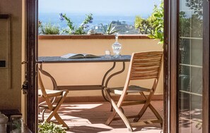Ein Balkon mit Tisch und zwei Stühlen, einem Buch, einem Glas und einer Flasche.