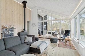 Een moderne woonkamer met een bank, een salontafel en een fauteuil. Een groot raam biedt uitzicht op het landschap.