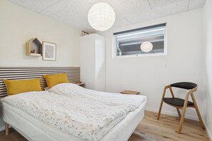 Une chambre à coucher comprenant un lit, une chaise, une fenêtre et une étagère fixée au mur.