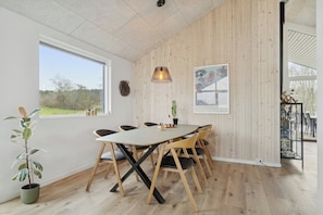 A dining area with a large table, chairs, and a hanging light fixture. - Stylish, energy-efficient holidayhome near by sea (Allingåbro)