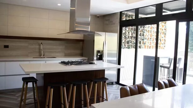 A modern kitchen with a central island, bar stools, and a dining table. - Moon Azul! (guatemala)