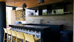 A modern kitchen with a large island, bar stools, and pendant lighting. - Moon Azul! (guatemala)