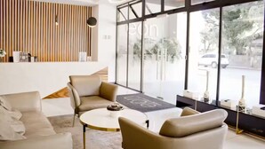 A modern interior with a sofa, armchairs, a coffee table, and a large window with a view of the street. - Moon Azul! (guatemala)