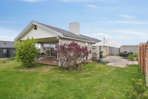 A residential house with a covered patio, a lawn, and a small garden area. - Cozy holiday home on Funen’s north coast (Bogense)