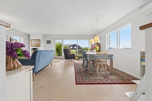 A spacious room with a dining area, a sofa, and a view of the outside. - Cozy holiday home on Funen’s north coast (Bogense)