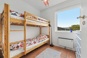 A bunk bed with floral bedding, a floor lamp, a radiator, and a window with a view of greenery. - Cozy holiday home on Funens north coast (Bogense)