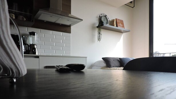 Una cucina moderna con piastrelle bianche a metro, una cappa in acciaio inossidabile e una macchina da caffè.