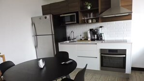 Una cucina moderna con un tavolo da pranzo nero, pensili bianchi e forno integrato.