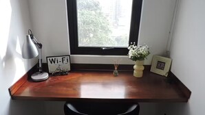 Una scrivania di legno con una sedia nera, una lampada, un segnale Wi-Fi, un piccolo vaso con fiori e un portafoto con la scritta "HOPE".