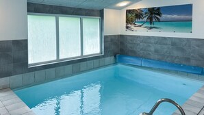 An indoor swimming pool with a view of a beach through frosted glass windows. - Lovely home in Væggerløse with sauna (Væggerløse)