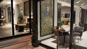 A modern interior with a seating area, a glass partition with artwork, and a small table with chairs. - Altuncu Premium Termal Hotel (Armutlu)