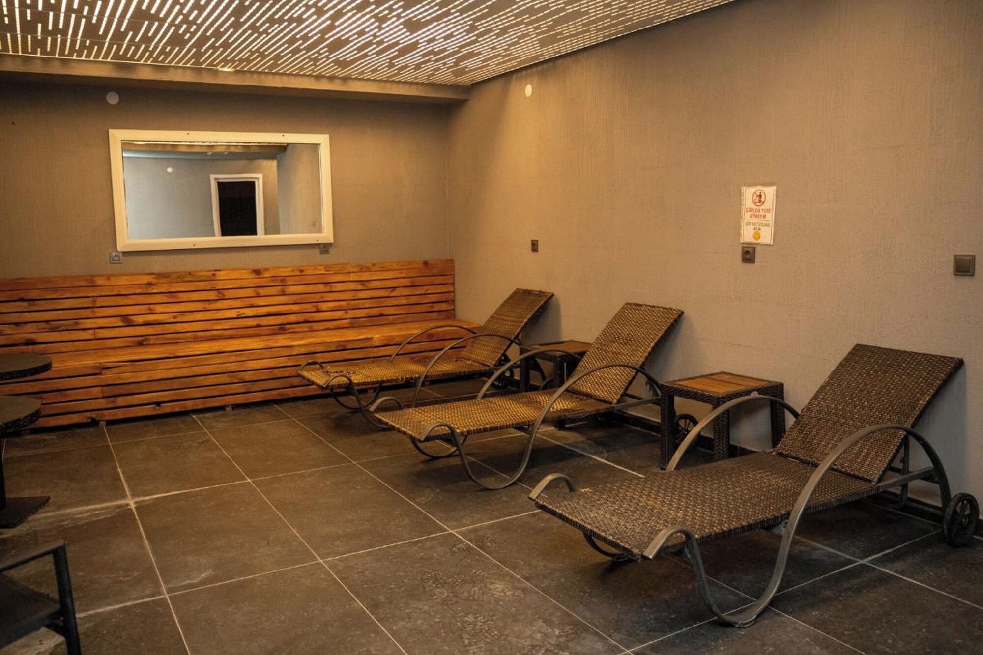 Une pièce comprenant un banc en bois, quatre fauteuils de jardin en osier et une petite table.