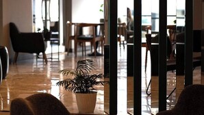 A modern interior with a polished floor, a potted plant, and a seating area with tables and chairs. - Altuncu Premium Termal Hotel (Armutlu)