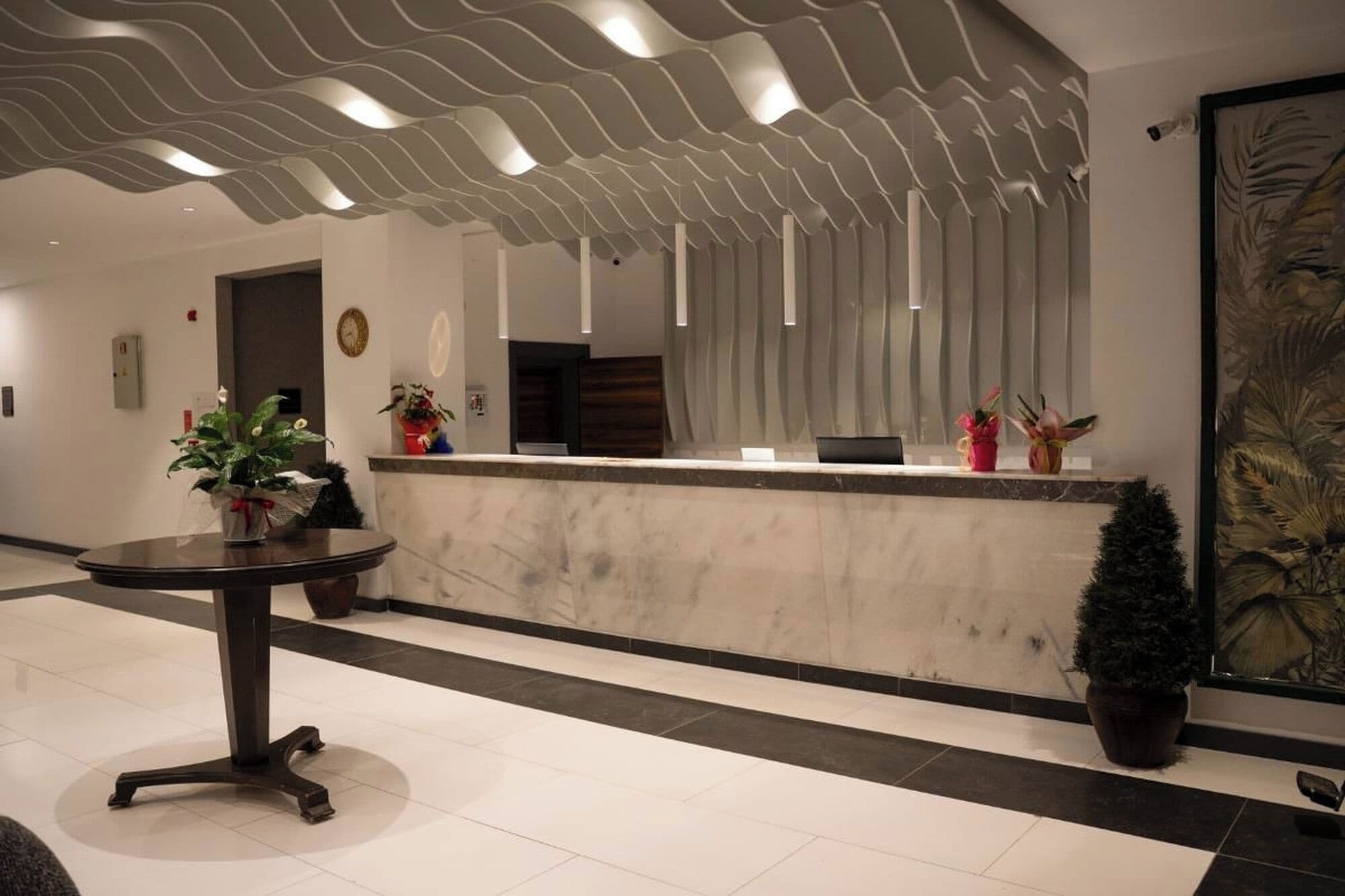 En moderne reception med en marmor disk, potteplanter og et unikt loftsdesign.