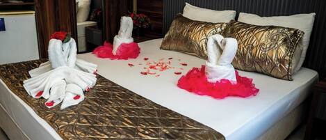 A hotel room with a bed, pillows, and a towel rack.