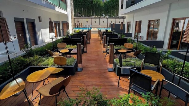 A courtyard with outdoor seating, a pool, and a view of a building in the background. - Altuncu Premium Termal Hotel (Armutlu)