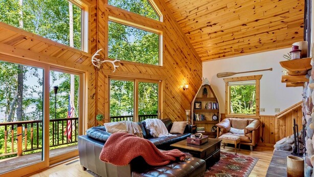 A spacious cabin with a large wooden ceiling, a cozy living area with a leather sofa, a fireplace, and a bookshelf. - NEW Sunset Serenity Lakefront Cabin wSauna & Private Dock: Kego Lake - Sleeps 10 (Fifty Lakes)
