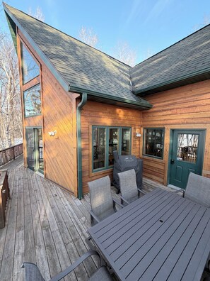 A wooden deck with outdoor seating and a barbecue grill.