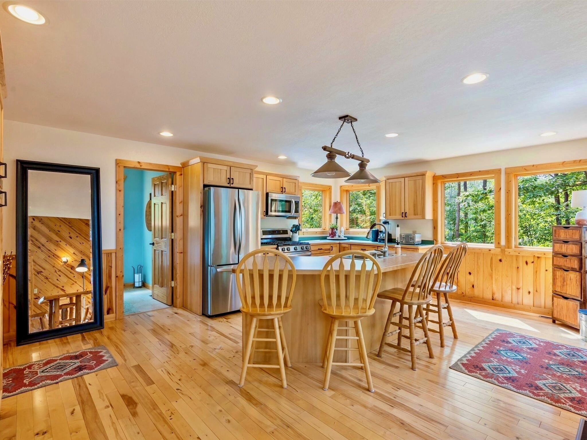 A modern kitchen with wooden cabinets, stainless steel appliances, and a large island with bar stools.