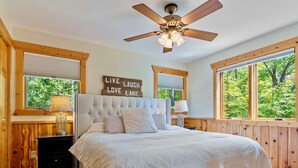 A bedroom with a large bed, wooden walls, and windows with blinds. - NEW Sunset Serenity Lakefront Cabin wSauna & Private Dock: Kego Lake - Sleeps 10 (Fifty Lakes)