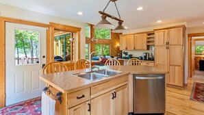 A spacious kitchen with wooden cabinets, a central island with a sink, and a built-in dishwasher. - NEW Sunset Serenity Lakefront Cabin wSauna & Private Dock: Kego Lake - Sleeps 10 (Fifty Lakes)
