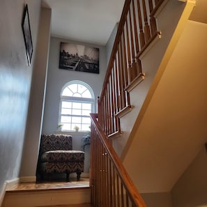 Un escalier avec des rampes en bois et une chaise à motifs au bas de l’escalier.