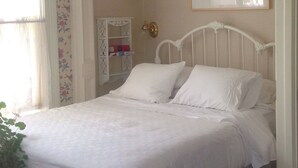 Een slaapkamer met een bed, een boekenkast en een ingelijst schilderij aan de muur.