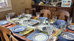 Een eettafel gedekt met blauwe en witte borden, glazen en houten stoelen.