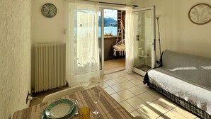 Una sala de estar con un sofá, una mesa de comedor con un mantel individual, un reloj y un equipo de aire acondicionado.