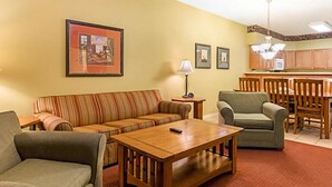 A living room with a sofa, armchair, coffee table, and a dining area with a table and chairs. - BLOCK Falls Village 1br (Angels Camp)