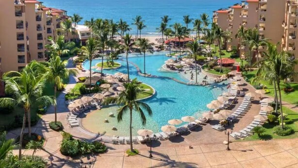 A resort with a central pool surrounded by palm trees and lounge chairs, overlooking the ocean. - Beautiful hotel suite with AC, beach access & fitness room in amazing Nayarit MX (Nay.)