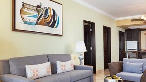 A living room with a grey sofa, a smaller sofa, a coffee table, and a painting on the wall. - Beautiful hotel suite with AC, beach access & fitness room in amazing Nayarit MX (Nay.)
