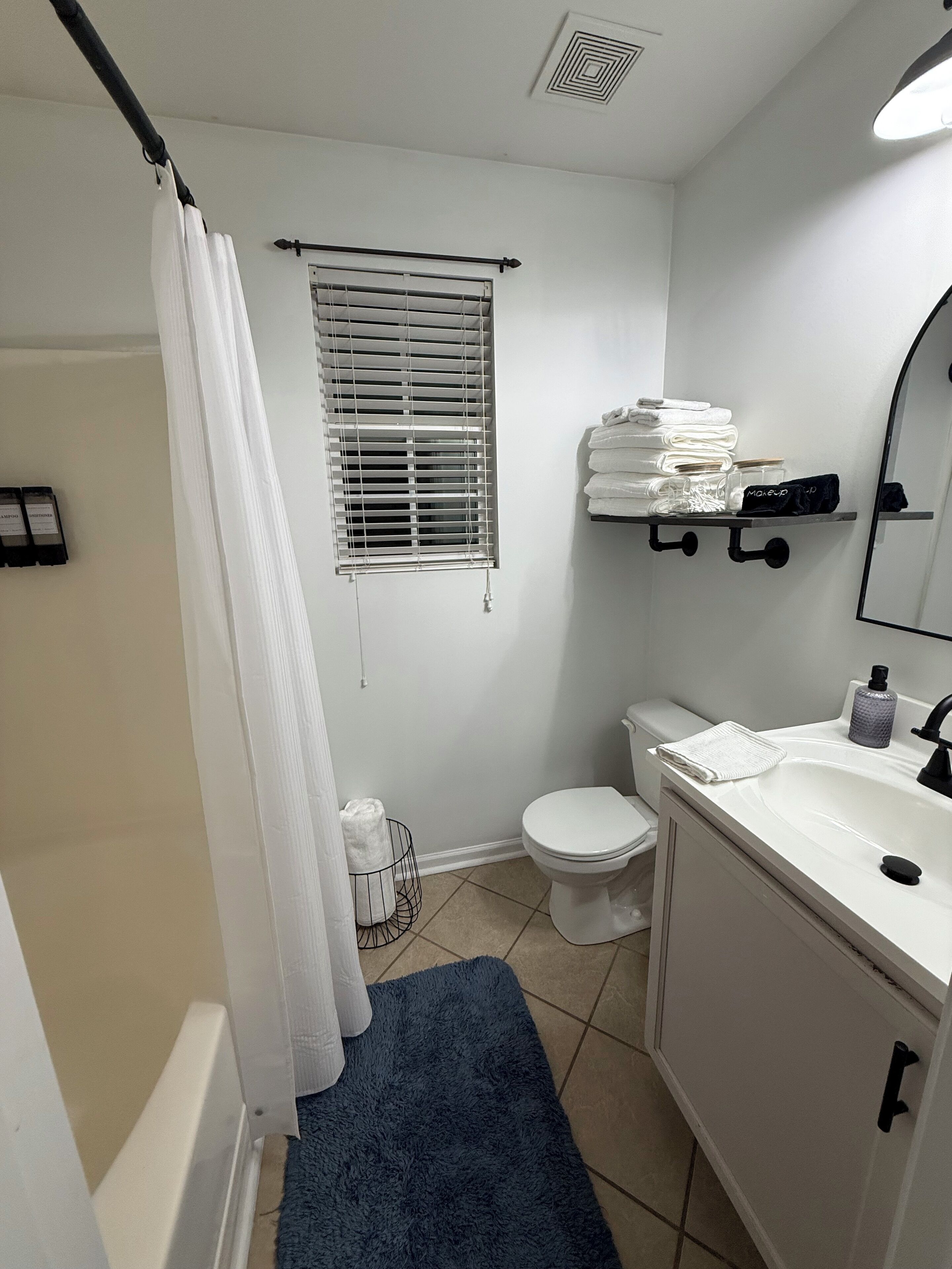 A bathroom with a toilet, sink, and window with blinds.