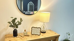 A wooden console table with a round mirror, a lamp, a sign, and a potted plant. - One story 4 bedroom updated ranch in the middle of it all. (Simpsonville)
